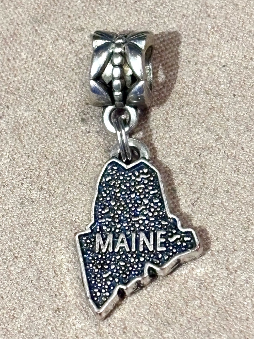 Maine charm in silver tone Shaped like the state MAINE in raised letters